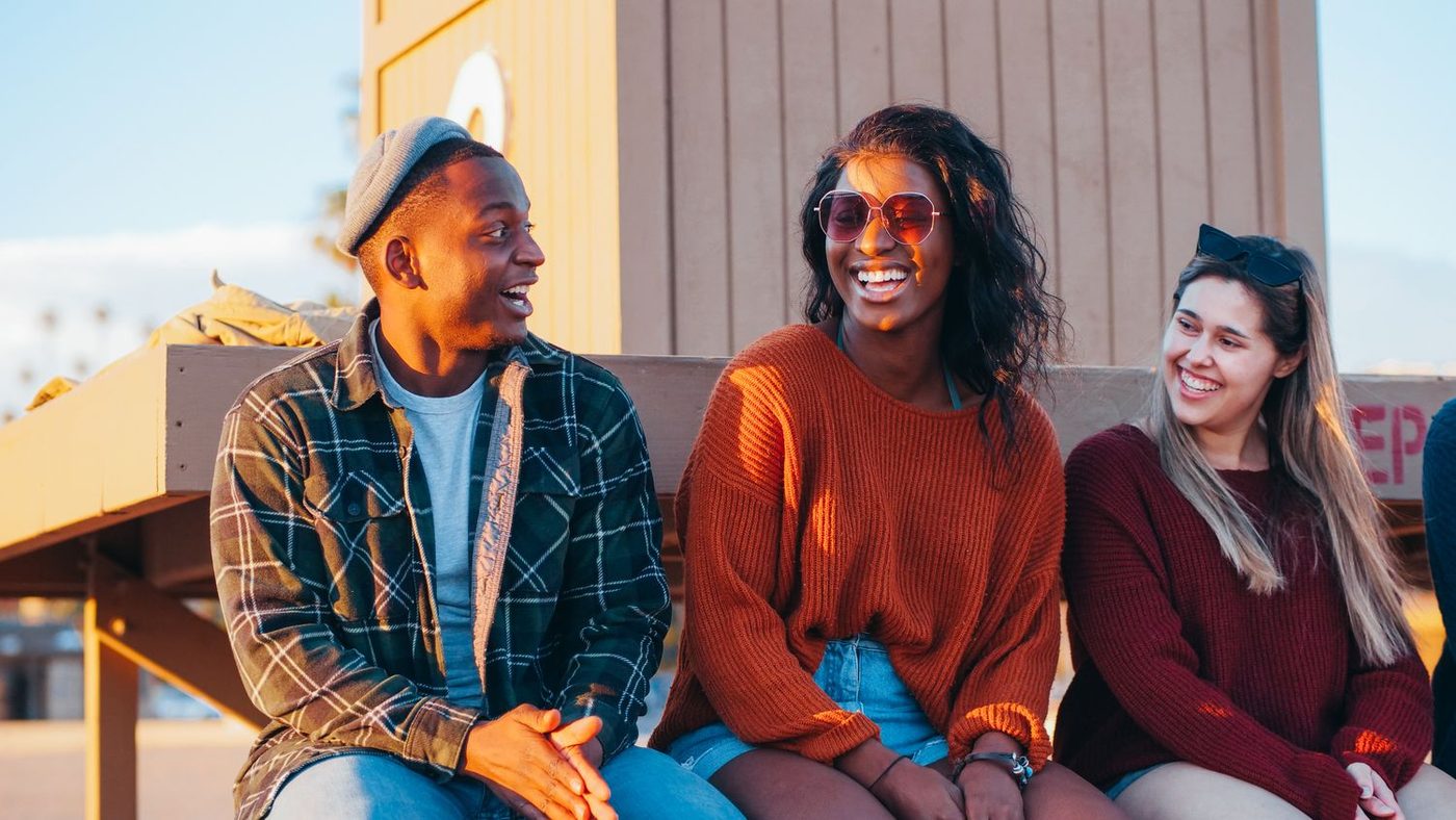 Three friends laughing together in warm evening light